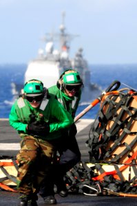 US Navy 100721-N-3659B-298 Logistics Specialist 3rd Class Brian Becker and Logistics Specialist 3rd Class James Heckwine run to safety after connecting a cargo pendant to an MH-60S Sea Hawk helicopter