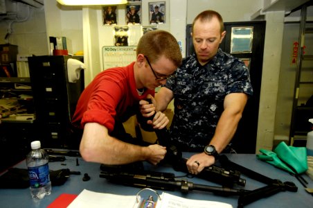 US Navy 100724-N-6362C-236 Gunner's Mate 2nd Class Nathan Shull assists Gunner's Mate 3rd Class James Langley in disassembling an M-240 machine gun