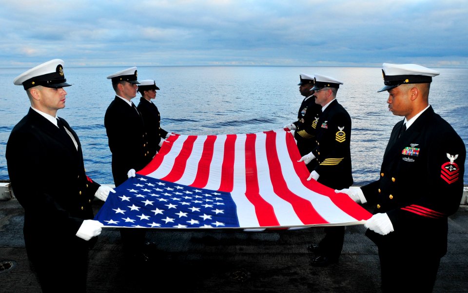 US Navy 100721-N-3595W-006 Sailors prepare to fold the national ensign during a sunrise burial at sea aboard USS Dwight D. Eisenhower (CVN 69)