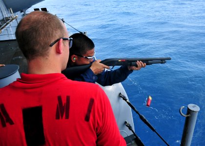 US Navy 100722-N-1287L-141 Aviation Ordnanceman 2nd Class Bobby K. Plunkett assists Aviation Ordnanceman Airman Recruit Adrian M. Galang with firing a 12-gauge