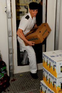 US Navy 100725-O-2032S-009 Master Corporal Luke Watson, from Calgary, a cook aboard the Canadian navy destroyer HMCS Algonquin (R17), brings a case of vegetables into the vegetable locker during replenishment at sea