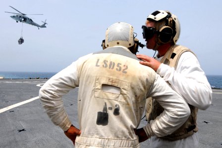US Navy 100722-N-7948R-021 Boatswain's Mate 1st Class Gregory Schaneville, right, communicates with Boatswain's Mate 1st Class David Coben as an MH-60S Sea Hawk helicopter