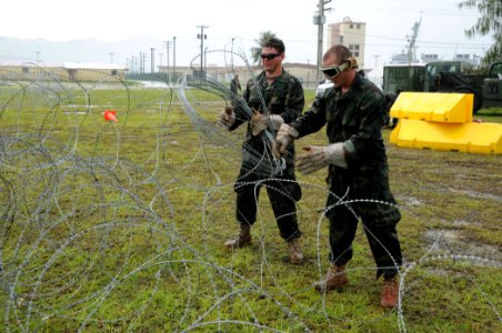 US Navy 100723-N-1906L-006 Master-at-Arms 3rd Class Anthony Lebya, left, and Master-at-Arms 3rd Class Jesse Van Winkle handle concertina wire to create a protective perimeter