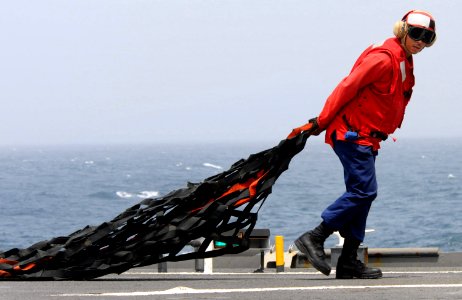 US Navy 100722-N-7948R-096 Damage Controlman 2nd Class Simon Guillory pulls a cargo net across the flight deck during a vertical replenishment aboard the amphibious dock landing ship USS Pearl Harbor (LSD 52) photo