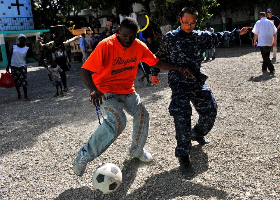 US Navy 100727-N-1531D-578 Boatswain's Mate Seaman Zhijian Chen, from Hong Kong, plays soccer with Haitian children during a Continuing Promise 2010
