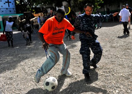 US Navy 100727-N-1531D-578 Boatswain's Mate Seaman Zhijian Chen, from Hong Kong, plays soccer with Haitian children during a Continuing Promise 2010