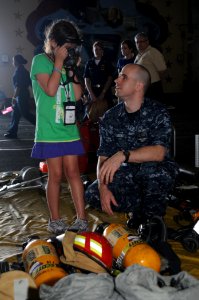 US Navy 100727-N-5085J-005 Hull Maintenance Technician 1st Class Michael Kubicki shows his sister Melissa a self-contained breathing apparatus aboard USS Dwight D. Eisenhower (CVN 69) during Tiger Cruise 2010