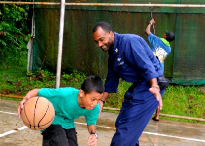 US Navy 100727-N-1675O-468 Religious Programs Specialist 1st Class Dana Saunders plays basketball with a Palauan child during a community service project at Melekeok Elementary School