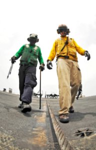 US Navy 100725-N-6003P-189 t. Russ White, right, and Aviation Boatswain's Mate (Handling) Airman Chad David inspect arresting wire three before aircraft land aboard the aircraft carrier USS Harry S. Truman (CVN 75)