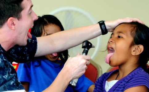 US Navy 100727-N-7478G-513 Lt. Cmdr. David Foster checks a patient's tonsils during a Pacific Partnership 2010 medical civic action project photo