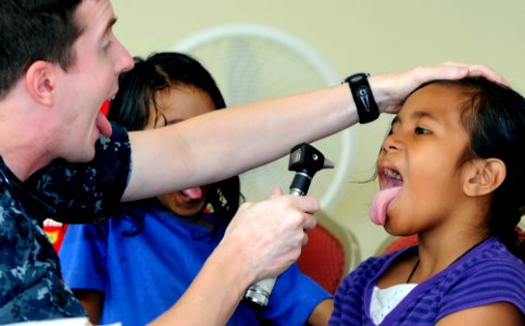 US Navy 100727-N-7478G-513 Lt. Cmdr. David Foster checks a patient's tonsils during a Pacific Partnership 2010 medical civic action project