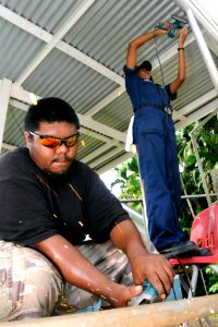 US Navy 100727-N-1675O-466 Seaman Apprentice Ashlie Booker and a Palaun man smooth sharp edges on metal fence poles during a Pacific Partnership 2010