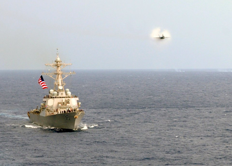 US Navy 100729-N-6935K-003 An F-A-18F Super Hornet assigned to the Jolly Rogers of Strike Fighter Squadron 103, performs a high-speed pass alongside the guide-missile destroyer USS Donald Cook (DDG 75)