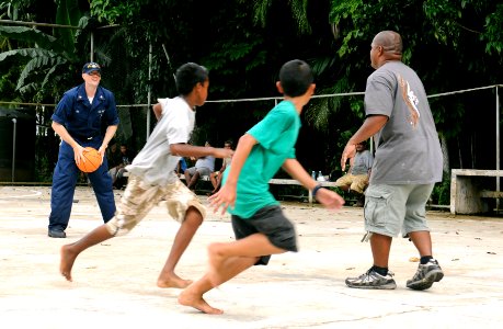 US Navy 100727-N-1675O-472 Electronics Technician 3rd Class Jared Jex prepares to pass a basketball to a Palauan child during a community service project at Melekeok Elementary School