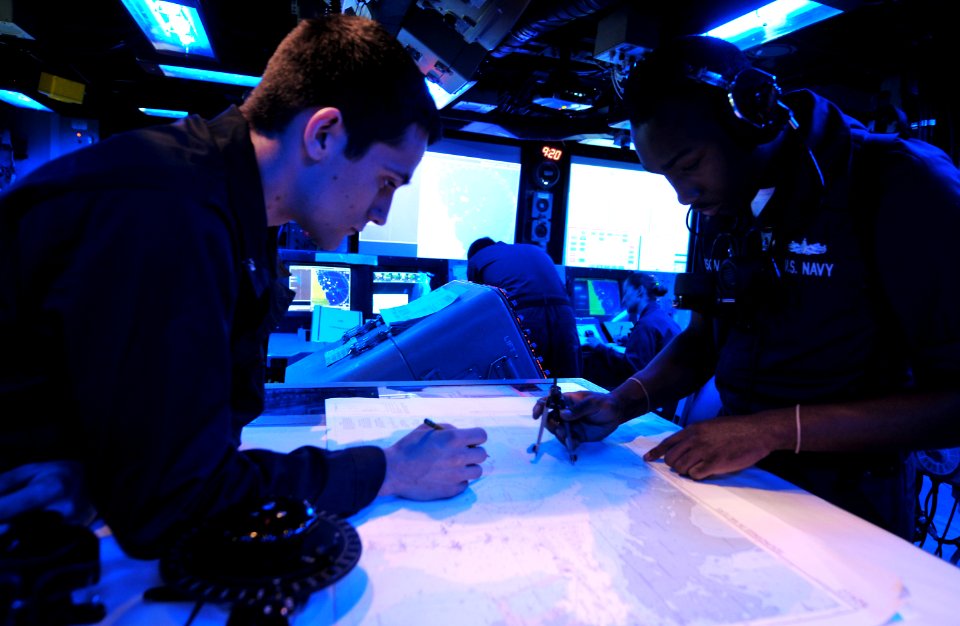 US Navy 100730-N-7948R-031 Operations Specialist Seaman Cortney Jackson, right, shows Midshipman 3rd Class Ryan Ewanchew how to plot a course on a chart aboard the amphibious dock landing ship USS Pearl Harbor (LSD 52)