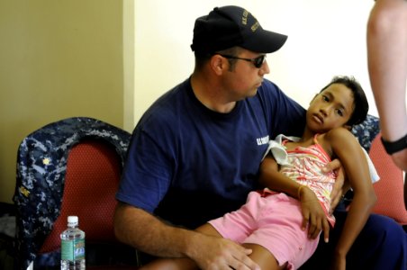 US Navy 100728-N-0864H-149 U.S. Coast Guard Gunner's Mate 2nd Class Nicholas Hallmark, assigned to Guam Coast Guard Sector, holds a sick child at a Pacific Partnership 2010 free medical clinic