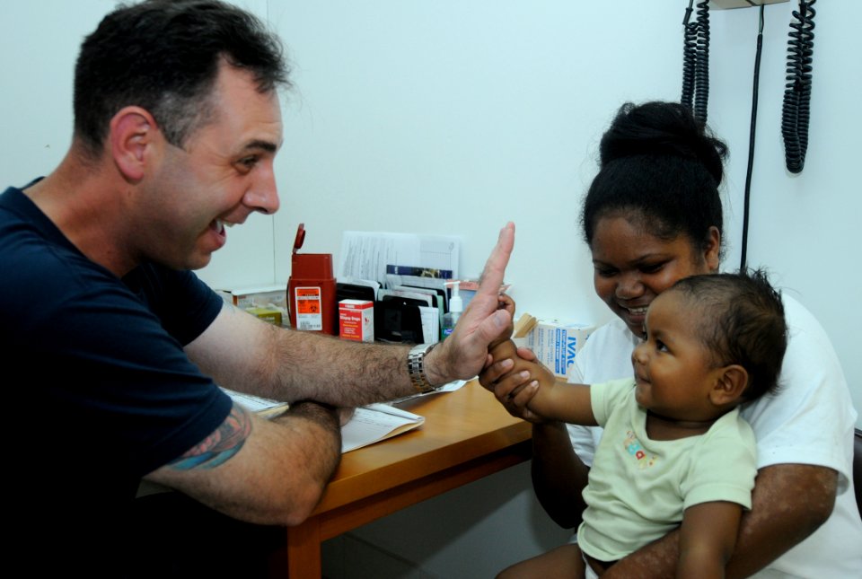 US Navy 100728-N-7280V-362 Senior Chief Hospital Corpsman Christopher Moore receives a high-five from a toddler after taking vitals at the Southern Community Health Center in the Republic of Palau