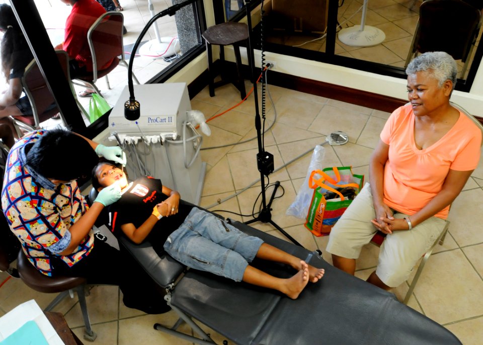US Navy 100729-N-4031K-205 Dr. Xavier Solis, from Palau National Hospital examines the teeth of Palauan child as her mother looks on at the Ngarachemayong Community Center