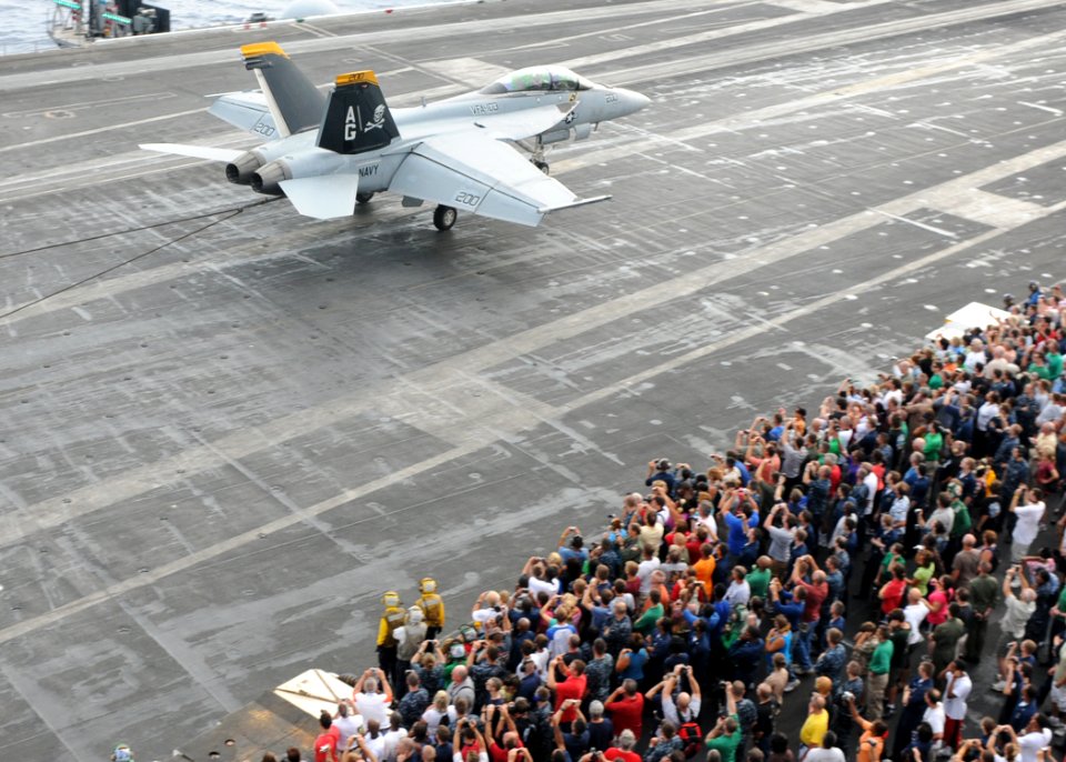 US Navy 100729-N-6935K-006 Sailors, their family and friends watch an F-A-18F Super Hornet assigned to the Jolly Rogers of Strike Fighter Squadron (VFA) 103,