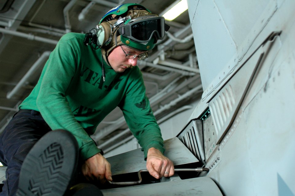 US Navy 100731-N-6427M-007 Aviation Electronics Technician 3rd Class Barry Styles replaces panels on a F-A-18C Hornet in the hangar bay of USS Harry S. Truman (CVN 75)