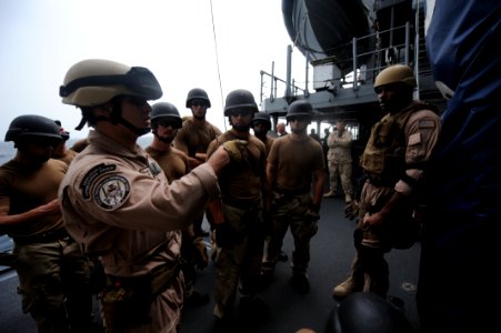 US Navy 100804-N-6463B-081 U.S. Coast Guard Machinery Technician 3rd Class Eric Ocasio, left, explains proper caving ladder techniques to Sailors assigned to the visit, board, search and seizure team