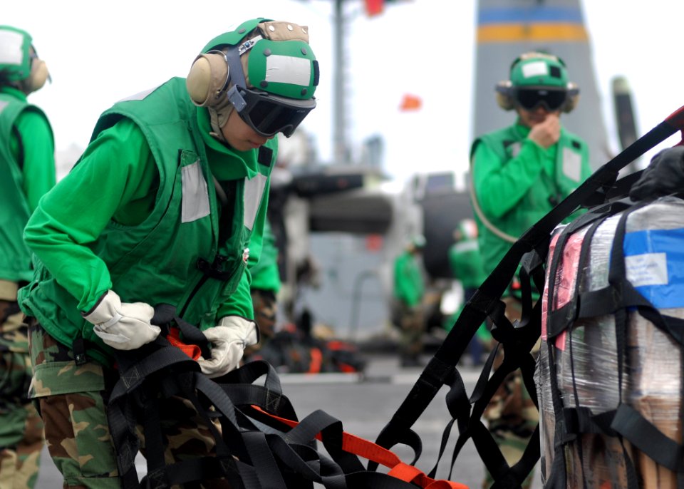 US Navy 100809-N-2013O-090 Logistics Specialist Seaman Xiao Yang Xing, from Queens, N.Y., removes cargo netting from a pallet of supplies aboard the aircraft carrier USS George Washington (CVN 73)