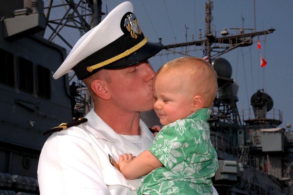 US Navy 100811-N-5292M-538 Ensign Colin Lyman kisses his nine-month-old son during a homecoming celebration for USS San Jacinto (CG 56). San Jacinto is returning from a seven-month deployment to the U.S. 5th and 6th Fleet areas