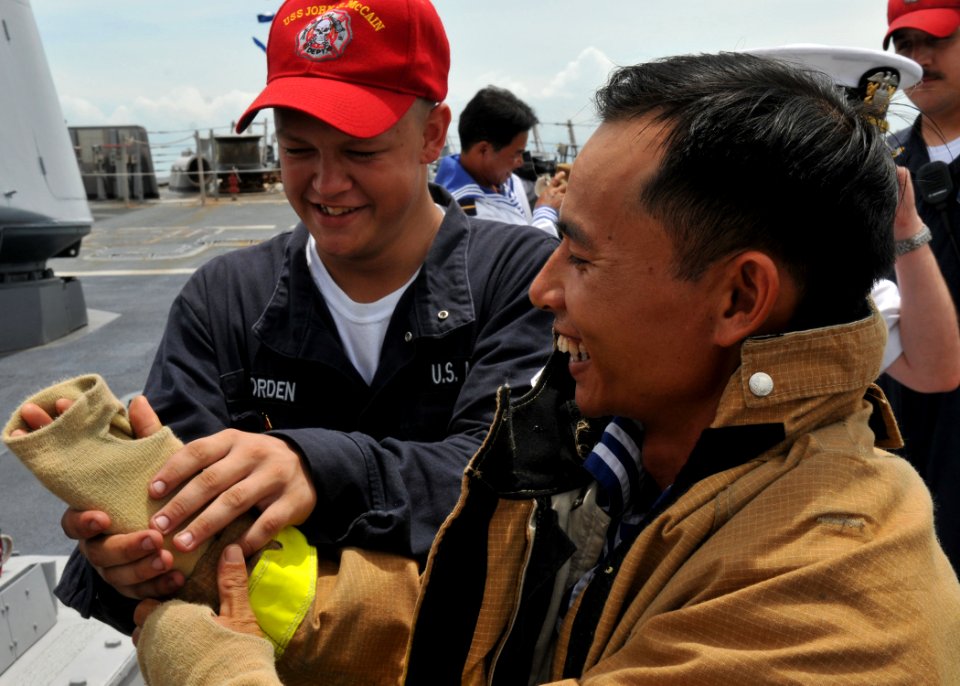 US Navy 100812-N-3215T-120 Hull Technician Fireman Apprentice Laurence Worden helps a Vietnam People's Navy sailor put on firefighting gloves during a damage control demonstration
