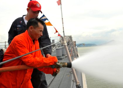 US Navy 100812-N-3215T-337 Damage Controlman 2nd Class Steven Galarza observes a Vietnam People's Navy sailor handle a fire hose during a damage control exchange aboard the ship