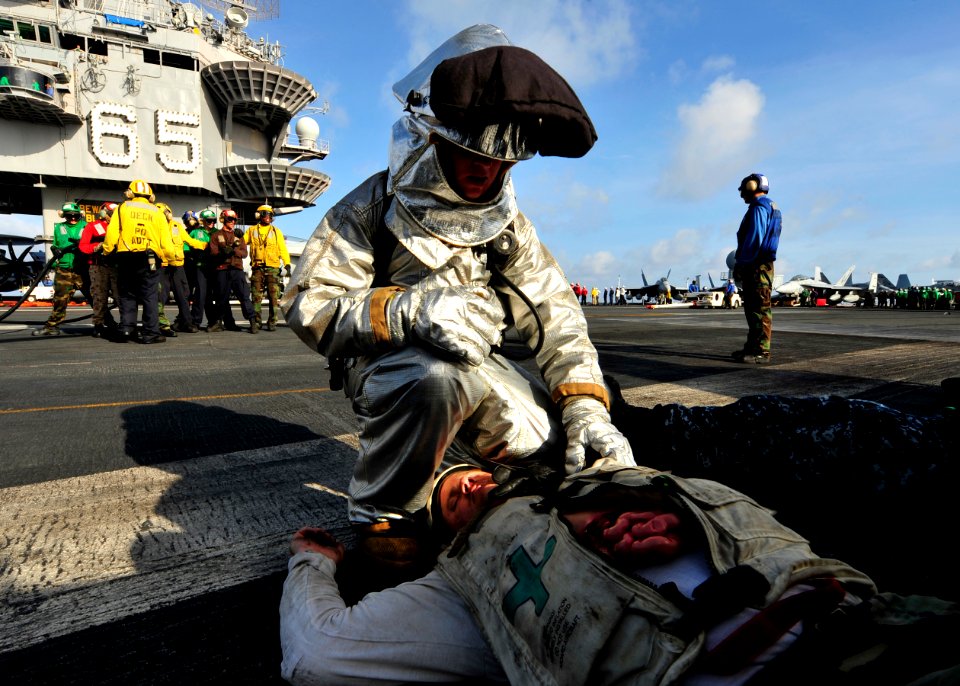 US Navy 100813-N-0569K-117 A member of the crash and salvage team assesses a Sailor's mock injuries during emergency drills on the flight deck of USS Enterprise (CVN 65)