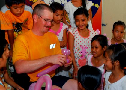 US Navy 100813-N-3589B-016 Master-at-Arms 1st Class Jonathan D. Baker makes balloon animals for Vietnamese children during a community service project at the Village of Hope orphanage photo
