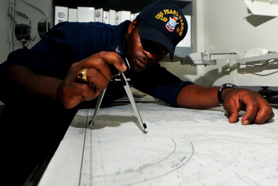 US Navy 100814-N-7948R-153 Quartermaster 2nd Class Marcus Dickerson plots the ship's position on a navigation chart aboard USS Pearl Harbor (LSD 52)
