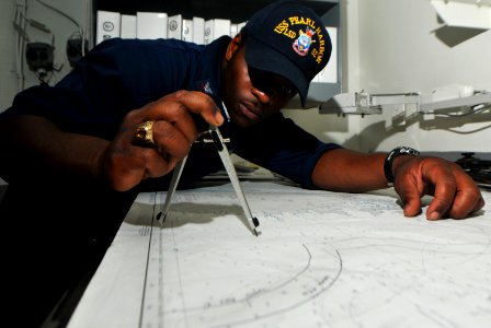 US Navy 100814-N-7948R-153 Quartermaster 2nd Class Marcus Dickerson plots the ship's position on a navigation chart aboard USS Pearl Harbor (LSD 52)