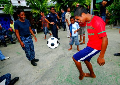 US Navy 100818-N-4044H-130 Aviation Maintenance Administrationman Ashley Mitchell, embarked aboard the Military Sealift Command hospital ship USNS Mercy (T-AH 19), plays soccer with a child during a community service event at S