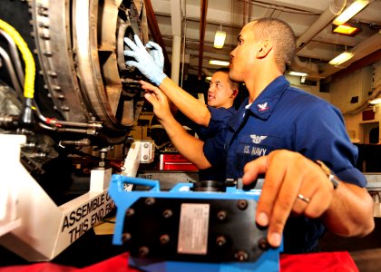 US Navy 100814-N-0569K-046 Aviation Machinist's Mate Airman Vinson C. Ya, left, and Aviation Machinist's Mate Airman 3rd Class Joshua R. Allen take out the low pressure turbine to inspect the F-A-18C hornet jet engine for debri