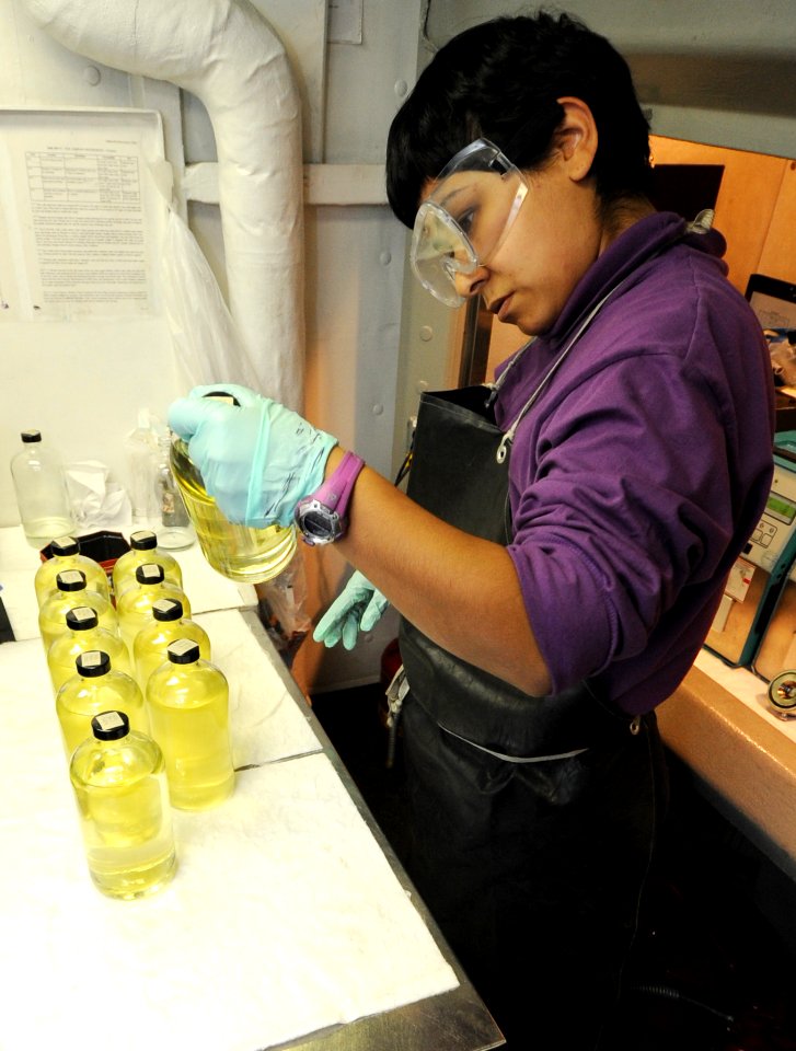 US Navy 100815-N-6362C-106 Aviation Boatswain's Mate (Fuel) Airman Amanda Martin inspects bottles of JP-5 aviation fuel for impurities during a water and sediment testing evolution aboard the aircraft carrier USS Harry S. Truma