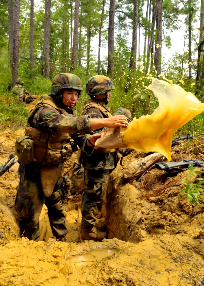 US Navy 100819-N-4440L-308 Lt. j.g. Victor Wong, assigned to Naval Mobile Construction Battalion (NMCB) 74, uses an empty Meal-Ready-to-Eat bag to bail his defensive fighting position
