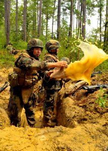 US Navy 100819-N-4440L-308 Lt. j.g. Victor Wong, assigned to Naval Mobile Construction Battalion (NMCB) 74, uses an empty Meal-Ready-to-Eat bag to bail his defensive fighting position