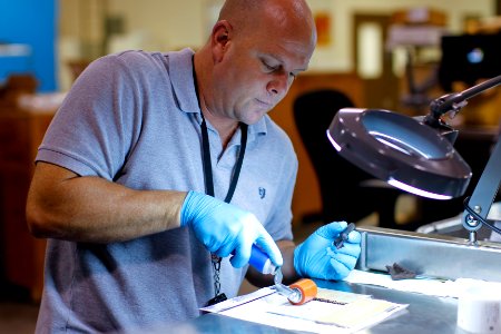 US Navy 100816-N-8863V-008 Steve VanWaus affixes labels bearing IUID marks to glass slides preparing for abrasion testing at Naval Surface Warfare Center, Corona Division