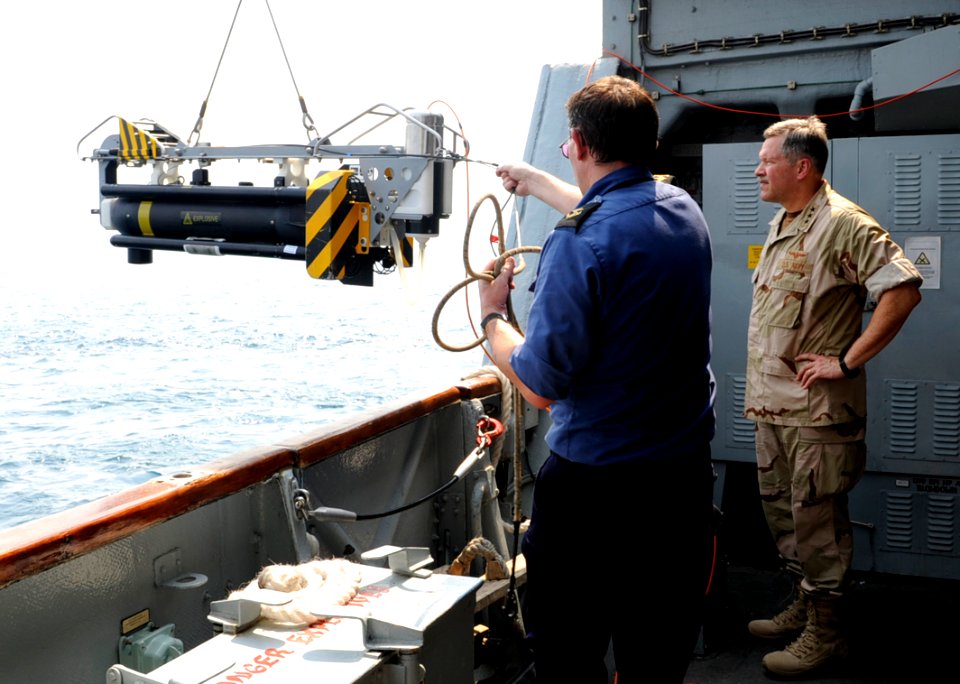 US Navy 100818-N-8959T-206 Vice Adm. Mark Fox, right, watches as the crew of HMS Chittingfold (M37) lowers Sea Fox, a mine neutralizer vehicle, into the water