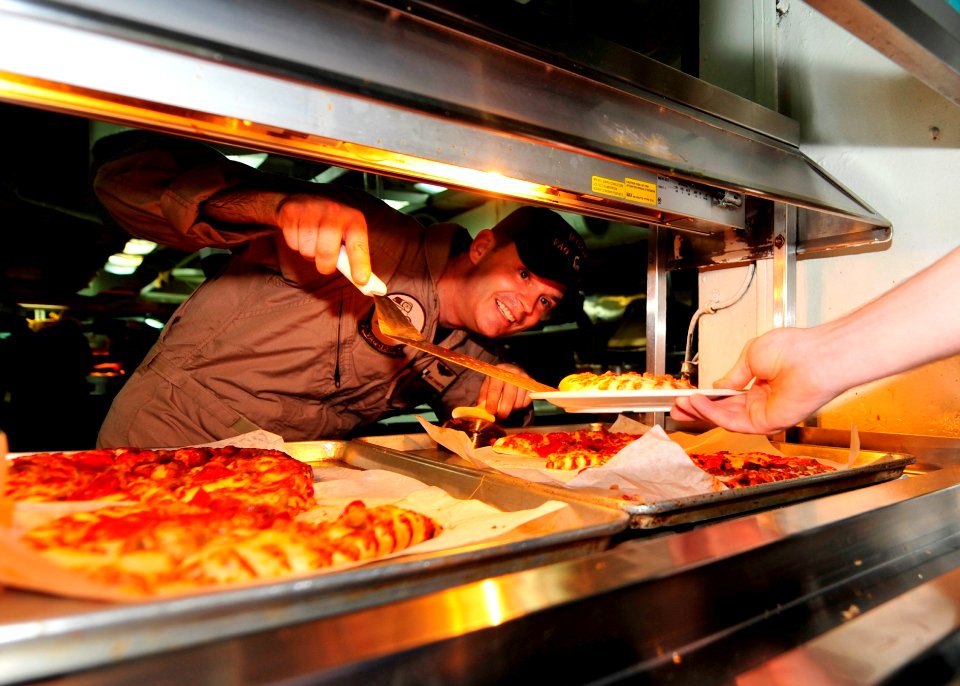 US Navy 100821-N-0569K-019 Cmdr. David V. Edgarton serves pizza to Sailors in the aft galley aboard USS Enterprise (CVN 65)