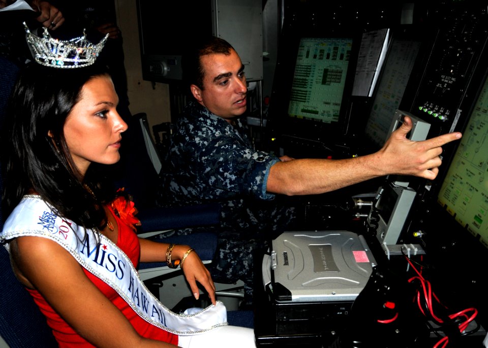 US Navy 100819-N-3560G-002 Electricians Mate 1st Class Allan Kleaving, assigned to the Virginia-class attack submarine USS Hawaii (SSN 776), explains basic submarine operations to Jalee Kate Fuselier, Miss Hawaii 2010