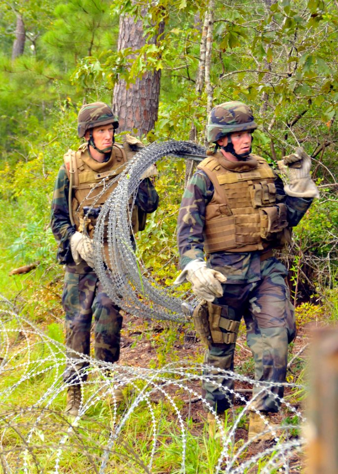 US Navy 100819-N-4440L-196 Cmdr. Richard Hayes III, commanding officer of Naval Mobile Construction Battalion (NMCB) 74, and Ensign James Schneider move concertina wire into position to set up a defensive line