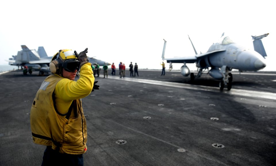 US Navy 100821-N-6362C-007 Aviation Boatswain's Mate (Handling) 1st Class Steve Temple directs an F-A-18C Hornet toward the catapults for launch aboard USS Harry S. Truman (CVN 75)