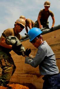 US Navy 100824-N-7280V-361 Equipment Operator 2nd Class Christopher Dain receives a sand bag from Republic of Korea (ROK) navy sailor Jeong Youngrok