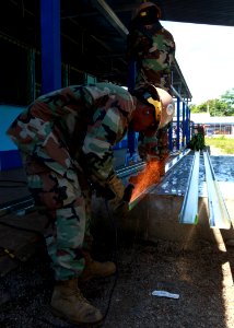 US Navy 100825-M-6740B-086 Utilitiesman 2nd Class Daurell Winchester, left, and other Seabees grind a metal ceiling support beam for a class room at Hone Creek School in Hone Creek, Costa Rica photo