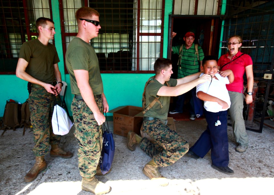 US Navy 100825-M-6740B-026 Sgt. Kyle W. Cucci gives a backpack to a student at Hone Creek primary school during a Continuing Promise 2010 community service project
