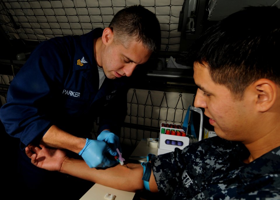 US Navy 100825-N-2686K-253 Hospital Corpsman 1st Class Carl R. Parker draws blood from Aviation Ordnanceman Airman Mychel D. Vannette
