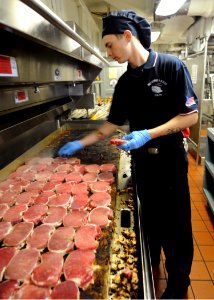US Navy 100821-N-2686K-030 Culinary Specialist Seaman Cody D. Cunningham prepares pork chops for lunch in the galley aboard USS George H.W. Bush (CVN 77)