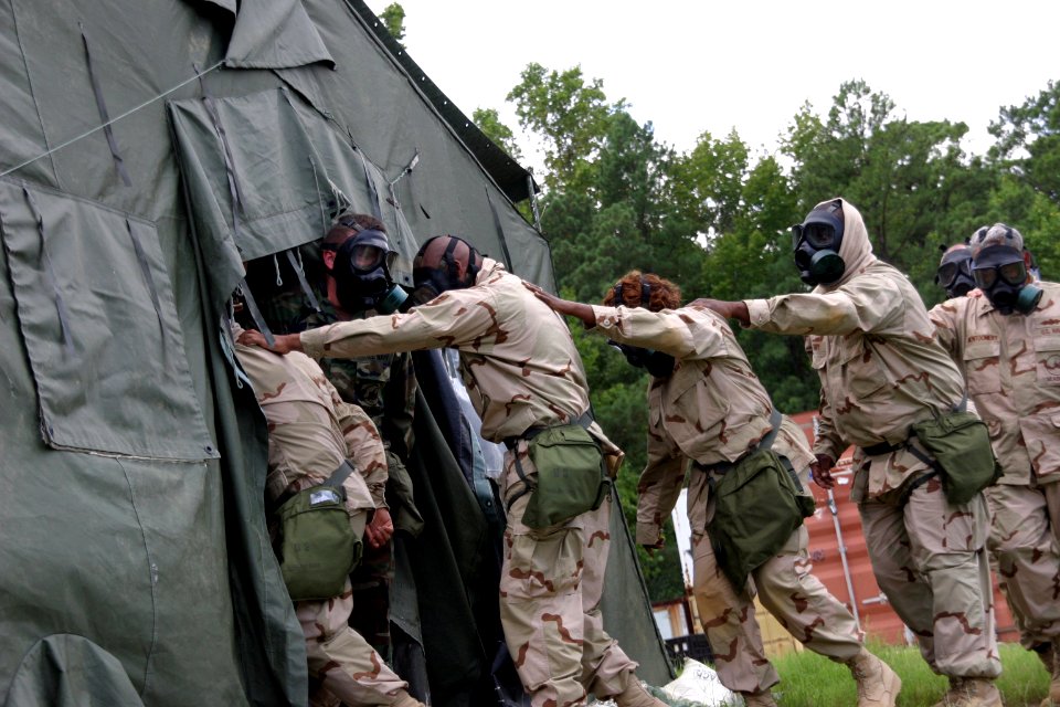 US Navy 100825-N-2888Q-001 Builder 1st Class Damian Warner holds the tent flap open as Sailors from NAVELSG Lima Rotation enter the confidence chamber